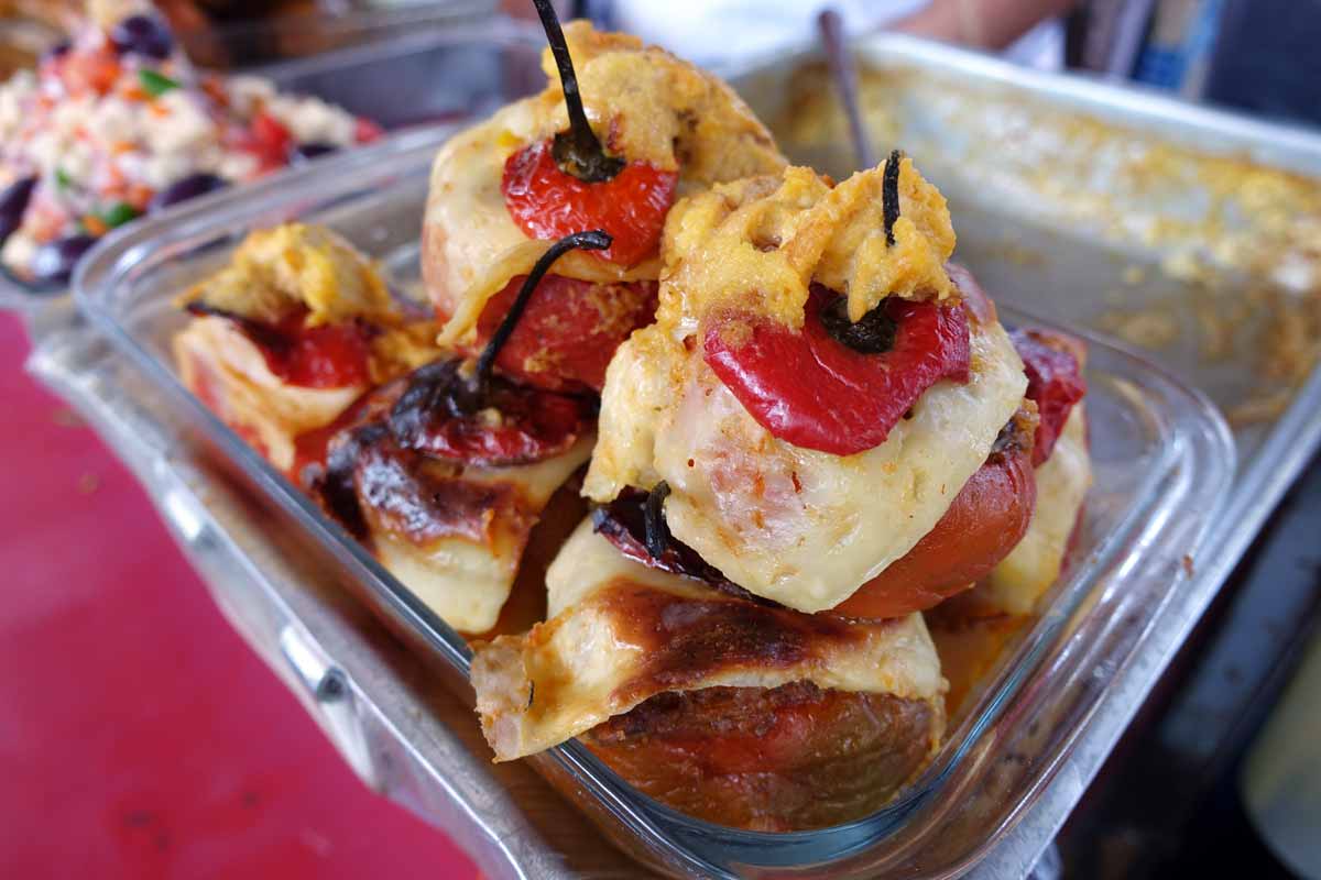 A glass tray with four stuffed red rocoto peppers covered in white melted cheese.